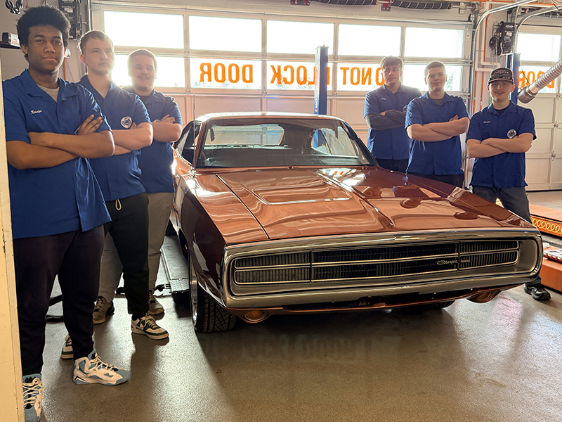 Class of 2026 students standing beside the 1970 Dodge Charger